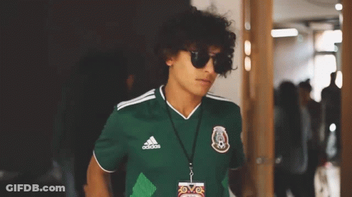 A Young Man Wearing Sunglasses And A Green Adidas Jersey GIF