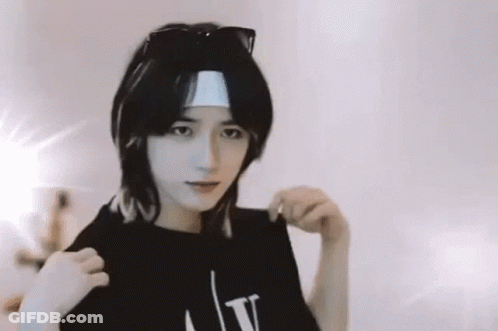 A Young Man Wearing Sunglasses And A Headband Is Standing In Front Of A Mirror . GIF
