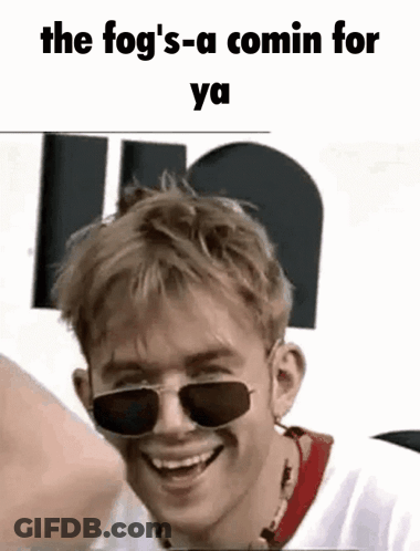 A Young Man Wearing Sunglasses Is Smiling And Laughing . GIF