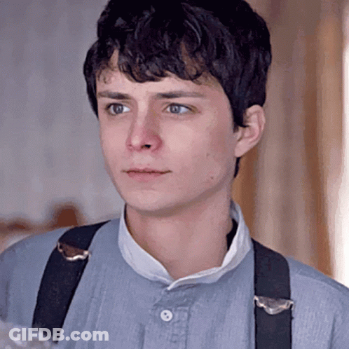 A Young Man Wearing Suspenders Is Looking At The Camera . GIF