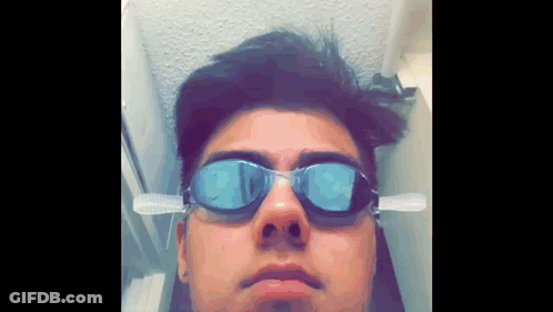 A Young Man Wearing Swimming Goggles With A Toothbrush Attached To His Ear GIF
