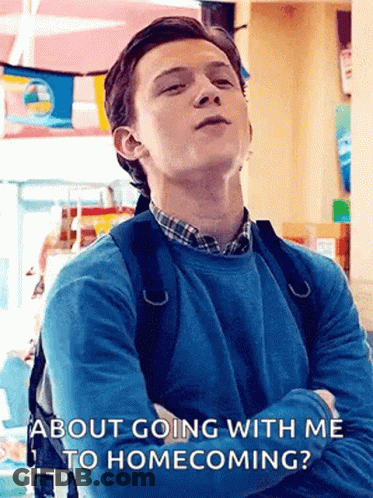 A Young Man With A Backpack Is Standing In A Room With His Arms Crossed And Talking About Going With Me To Homecoming . GIF