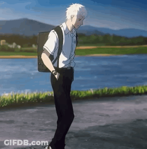 A Young Man With A Backpack Is Walking Down A Street . GIF