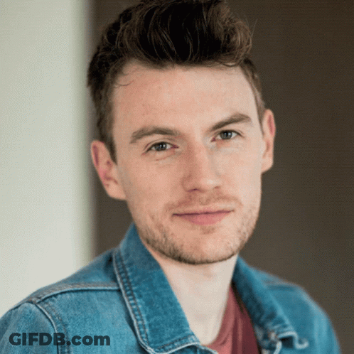 A Young Man With A Beard Wearing A Blue Denim Jacket GIF