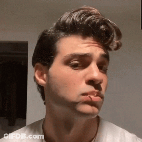 A Young Man With A Cigarette In His Mouth Looks At The Camera GIF