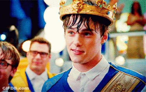 A Young Man With A Crown On His Head Stands In Front Of A Group Of Men GIF