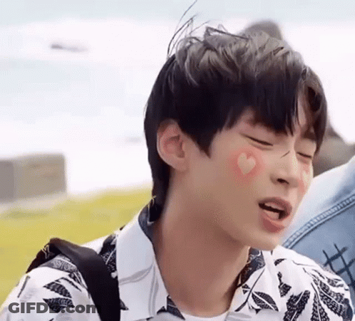 A Young Man With A Heart On His Cheek Is Making A Face . GIF