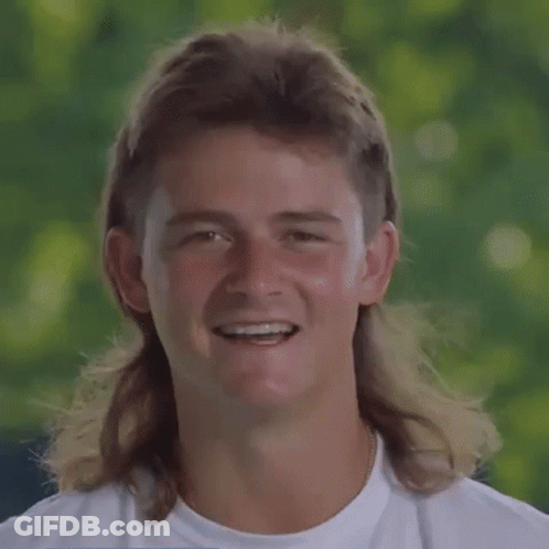 A Young Man With A Mullet And Braces On His Teeth Is Smiling . GIF