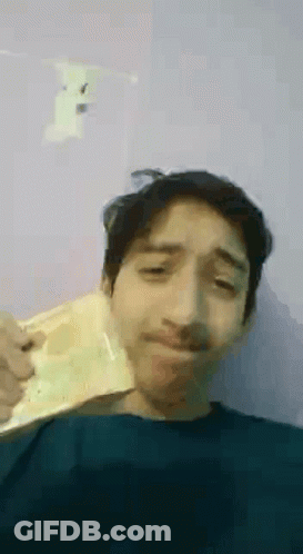 A Young Man With A Mustache Is Holding A Piece Of Paper In His Hand . GIF