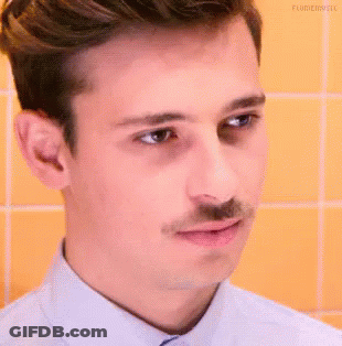 A Young Man With A Mustache Is Making A Funny Face . GIF