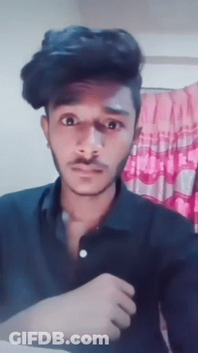 A Young Man With A Mustache Is Making A Funny Face While Wearing A Black Shirt . GIF