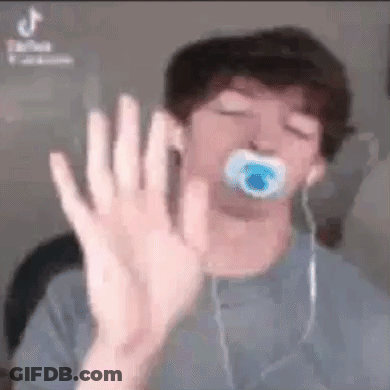 A Young Man With A Pacifier In His Mouth Is Making A Stop Sign With His Hand . GIF