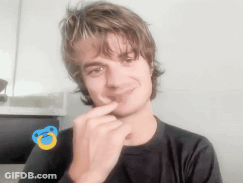 A Young Man With A Pacifier On His Finger Is Smiling GIF