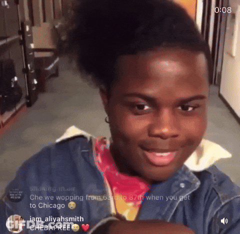 A Young Man With A Ponytail Is Smiling And Looking At The Camera With The Time Of 0:08 Behind Him GIF