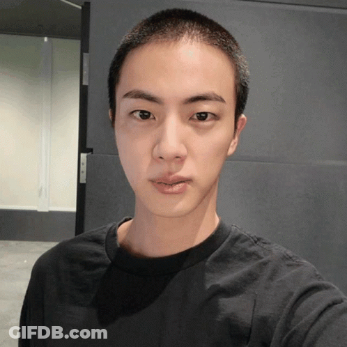 A Young Man With A Shaved Head Looks At The Camera GIF