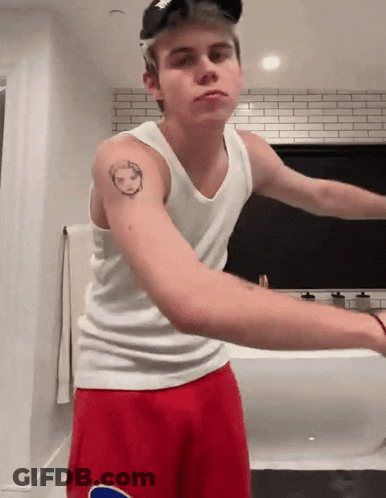 A Young Man With A Tattoo On His Arm Wearing Red Shorts GIF