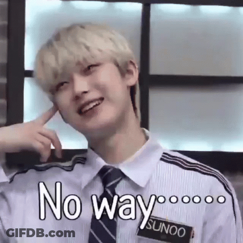 A Young Man With Blonde Hair And A Tie Is Smiling And Making A Funny Face With His Finger In His Ear . GIF