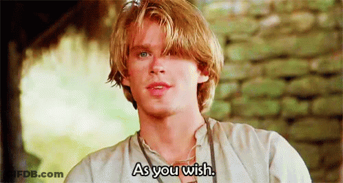A Young Man With Blonde Hair And Blue Eyes Is Standing In Front Of A Stone Wall . GIF
