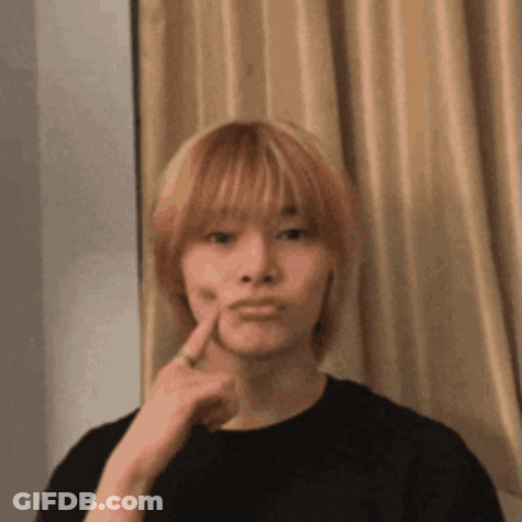 A Young Man With Blonde Hair Is Making A Funny Face While Holding His Finger To His Face . GIF