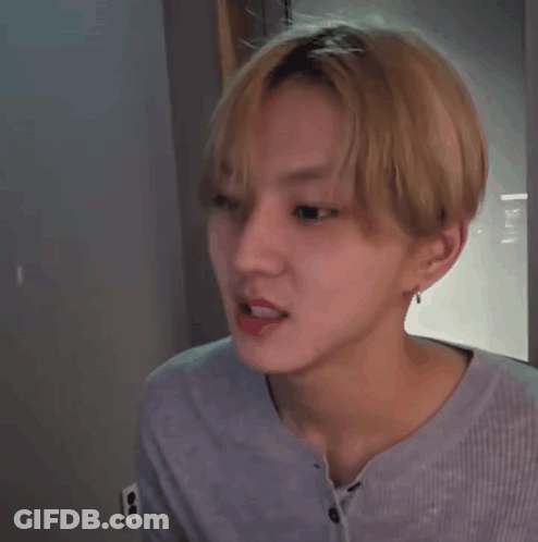 A Young Man With Blonde Hair Is Making A Funny Face While Wearing A Blue Shirt . GIF