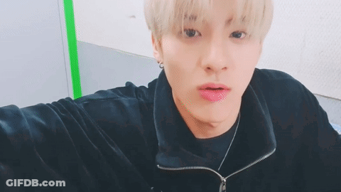 A Young Man With Blonde Hair Is Taking A Selfie While Wearing A Black Jacket And Necklace . GIF