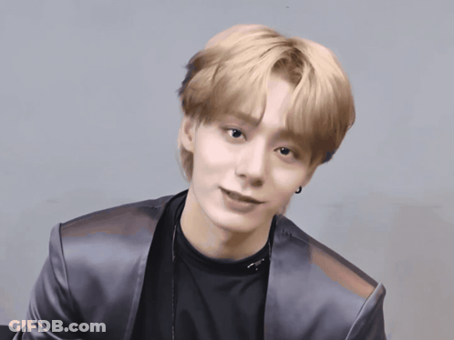 A Young Man With Blonde Hair Is Wearing A Black Shirt And Silver Jacket GIF