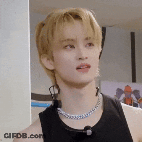 A Young Man With Blonde Hair Is Wearing A Black Tank Top And A Silver Chain Necklace . GIF