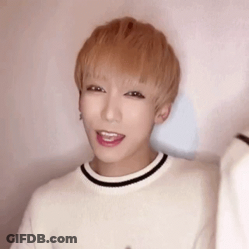 A Young Man With Blonde Hair Is Wearing A White Sweater With A Black Stripe Around The Neck . GIF