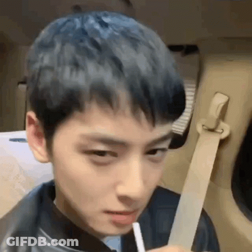 A Young Man With Blue Hair Is Sitting In The Back Seat Of A Car Holding A Straw . GIF