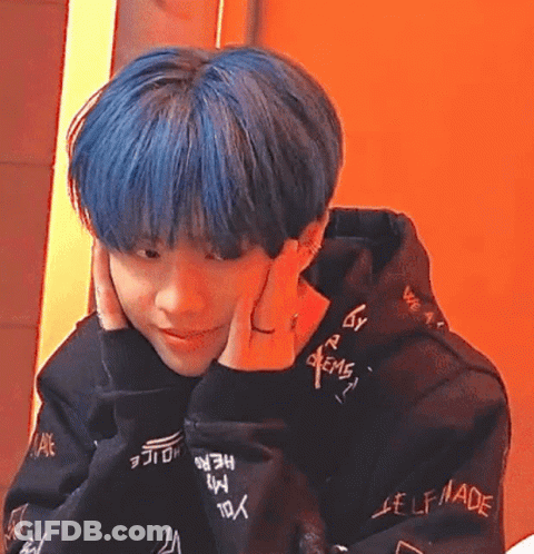 A Young Man With Blue Hair Is Wearing A Black Hoodie And A Ring On His Finger . GIF