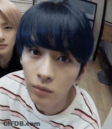 A Young Man With Blue Hair Is Wearing A Striped Shirt And Looking At The Camera . GIF