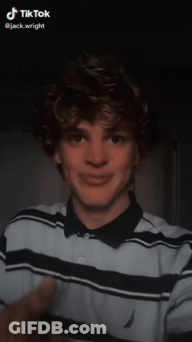 A Young Man With Braces On His Teeth Is Wearing A Blue And Black Striped Shirt And A Ring On His Finger GIF