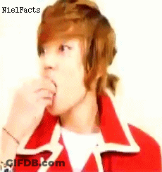 A Young Man With Brown Hair Is Wearing A Red Jacket And Eating Something . GIF