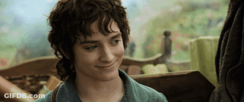 A Young Man With Curly Hair And A Green Shirt Smiles GIF