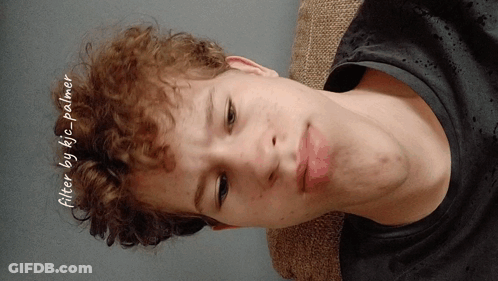 A Young Man With Curly Hair Is Laying On A Couch With The Words Filter By Kic Palmer Written On The Bottom GIF