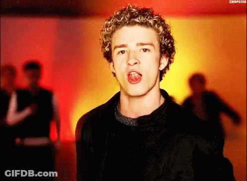 A Young Man With Curly Hair Is Singing Into The Camera . GIF