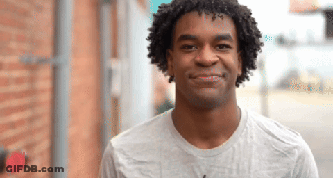 A Young Man With Curly Hair Is Smiling For The Camera GIF