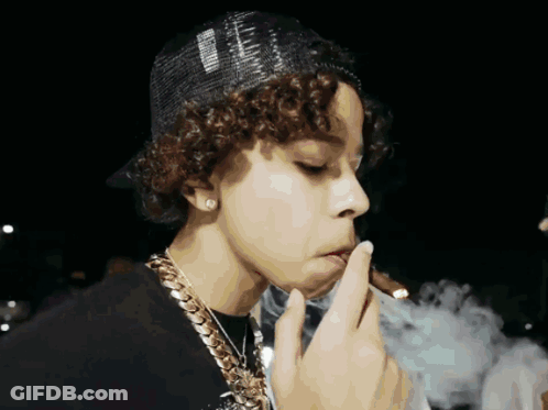 A Young Man With Curly Hair Is Smoking A Cigarette And Wearing A Hat That Says ' Supreme ' On It GIF