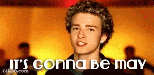 A Young Man With Curly Hair Is Standing In Front Of A Yellow Background With The Words `` It 'S Gonna Be May '' . GIF