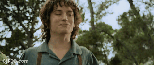 A Young Man With Curly Hair Is Standing In Front Of Trees GIF