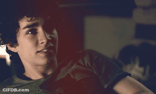 A Young Man With Curly Hair Is Wearing A Black T-Shirt GIF