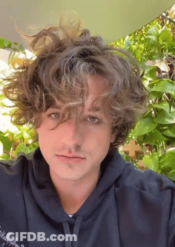 A Young Man With Curly Hair Is Wearing A Blue Hoodie GIF