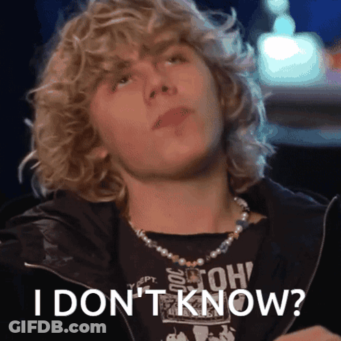 A Young Man With Curly Hair Is Wearing A Pearl Necklace And A Black Shirt That Says " I Don 'T Know " GIF
