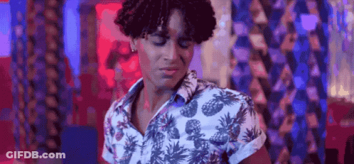 A Young Man With Curly Hair Is Wearing A Pineapple Shirt And Dancing In A Club . GIF