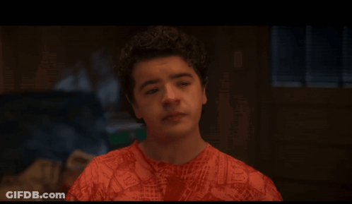 A Young Man With Curly Hair Is Wearing A Red Shirt With A Pattern Of Letters GIF