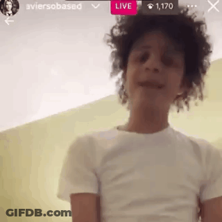 A Young Man With Curly Hair Is Wearing A White T-Shirt And Talking On A Video Call . GIF