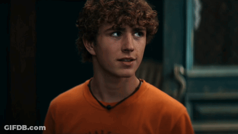 A Young Man With Curly Hair Is Wearing An Orange Shirt That Says Abercrombie GIF
