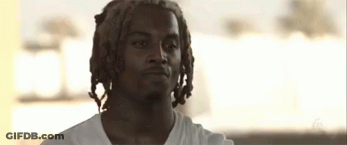 A Young Man With Dreadlocks And A Beard Is Wearing A White Shirt GIF