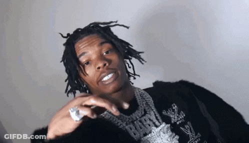 A Young Man With Dreadlocks And A Ring On His Finger Is Wearing A Black Jacket And A Necklace . GIF