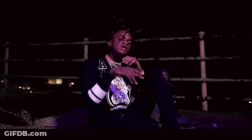 A Young Man With Dreadlocks Is Smoking A Cigarette In A Dark Room . GIF